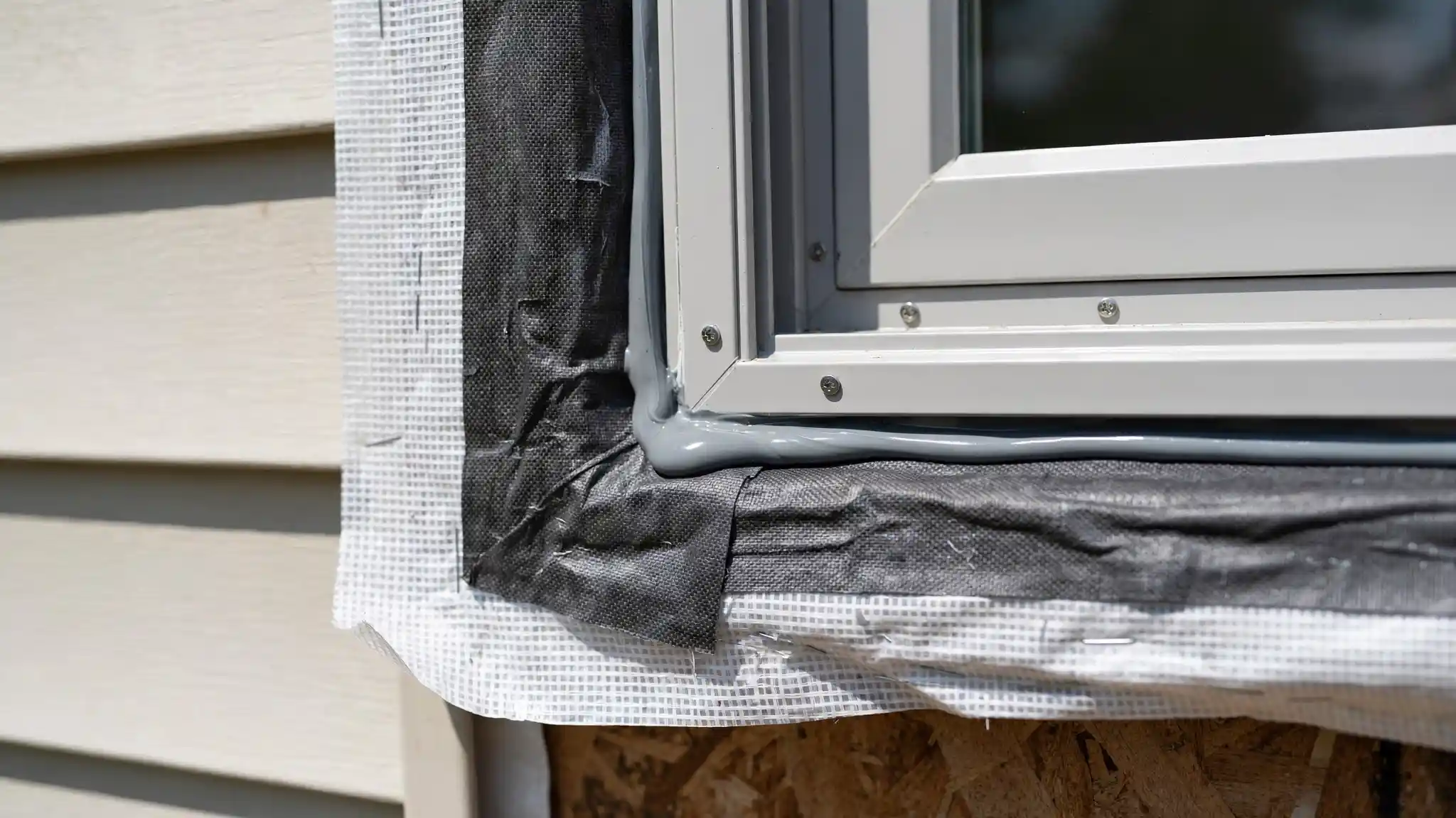 Close-up of window flashing tape and caulking detail around a new window frame